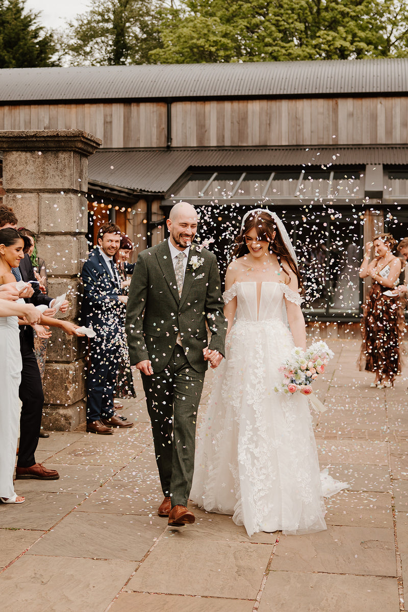 A professional image of a couple being showered with confetti at a wedding