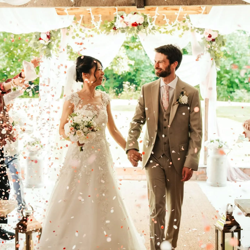 A couple at an indoor ceremony with guests throwing Confetti