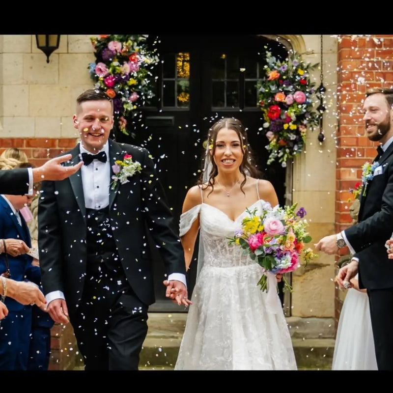 A couple being showered with SnowPetal real petal confetti at a wedding